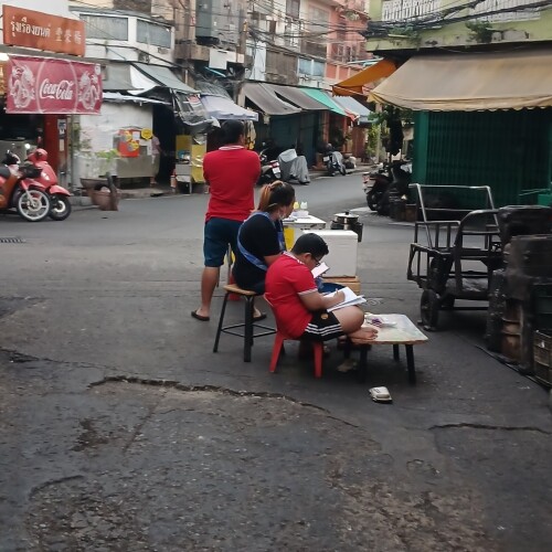 A family goes as fresco in Talat Noi, while the boy does his homework.